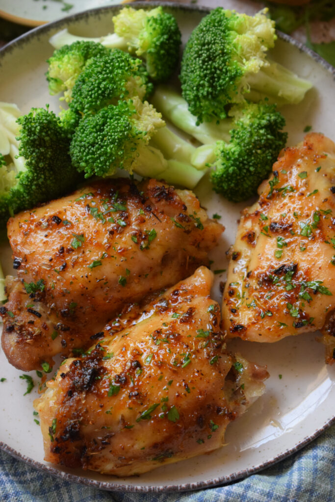 Baked chicken thighs on a plate with broccoli.