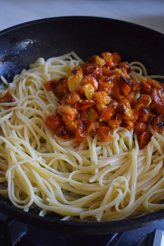 Linguine and roasted tomatoes in a skillet.