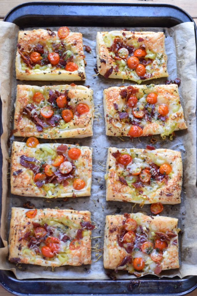 Tomato leek and bacon tarts on a baking tray.