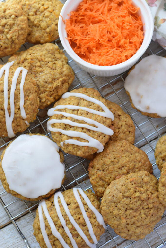 Carrot cake cookies on a rack with grated carrots.