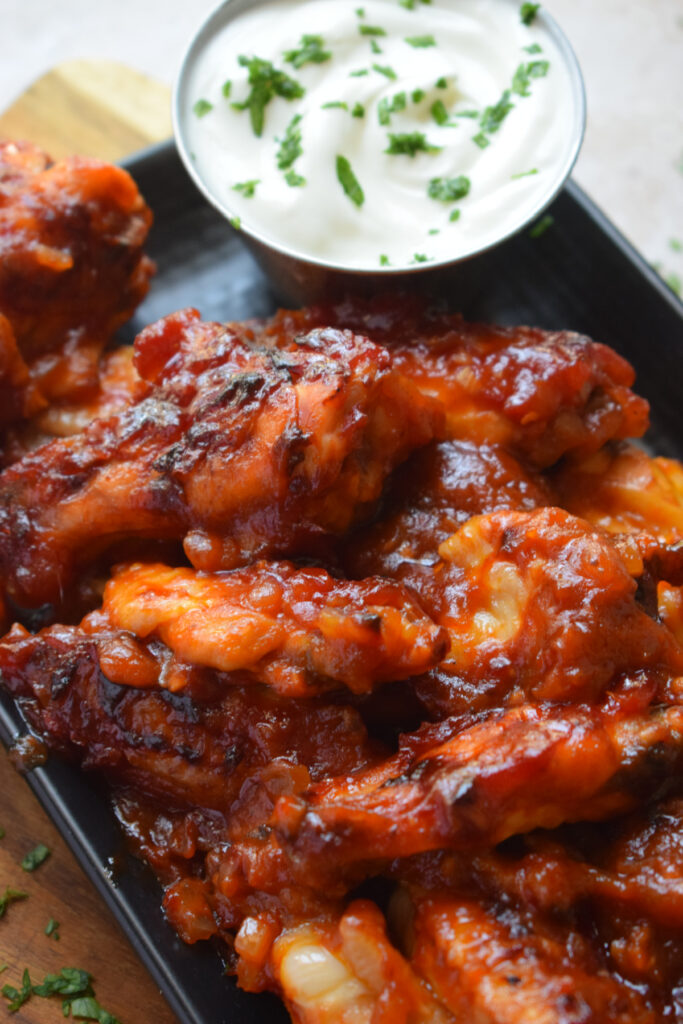 Close up of chicken wings on a black plate.