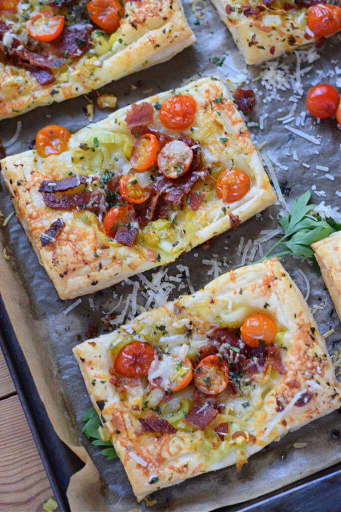 Tomato leek and bacon tarts on a baking tray.