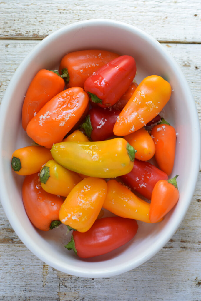 Mini peppers in a white dish ready to roast.