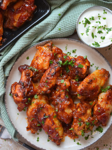 Sauce smothered wings on a white plate.