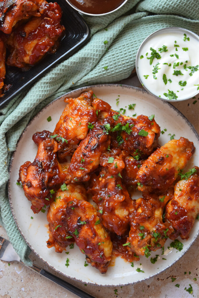 Sauce smothered wings on a white plate.