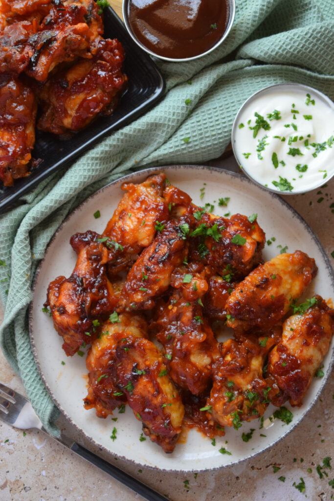 Oven barbecue wings on a plate with a dipping sauce.