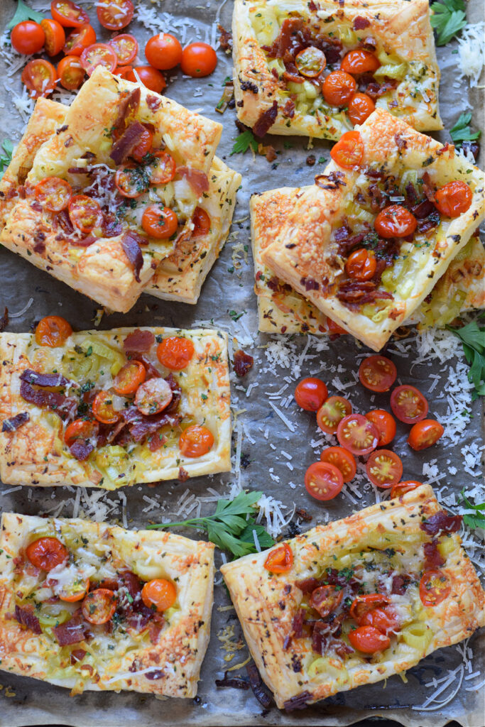 Tomato leek and bacon tarts on a baking tray.