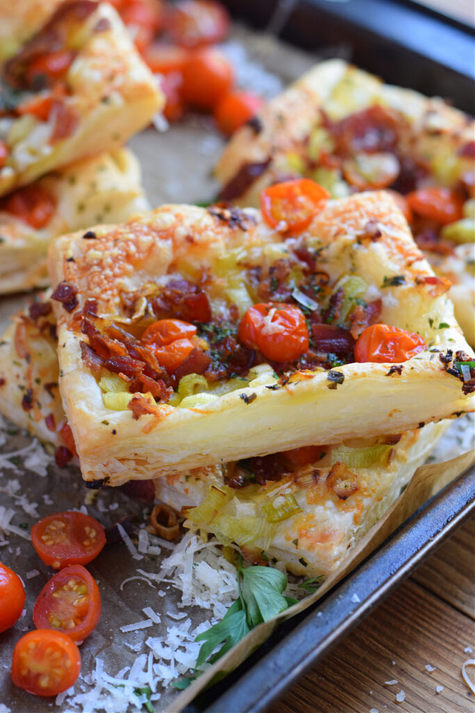 Tomato leek and bacon tarts on a baking tray.