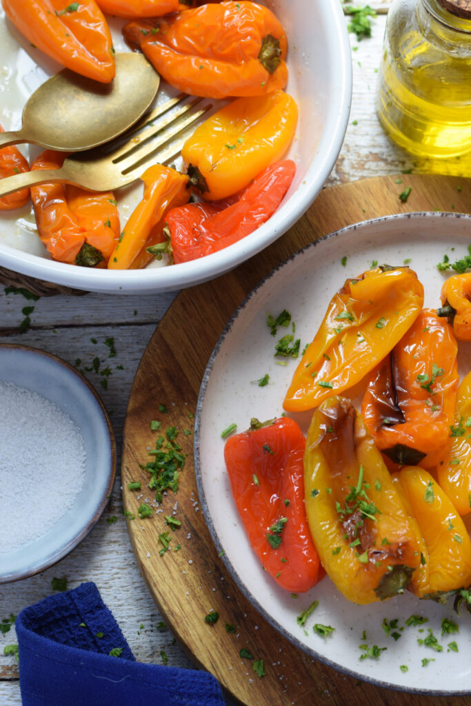 Roasted sweet mini peppers on a plate with salt and olive oil.