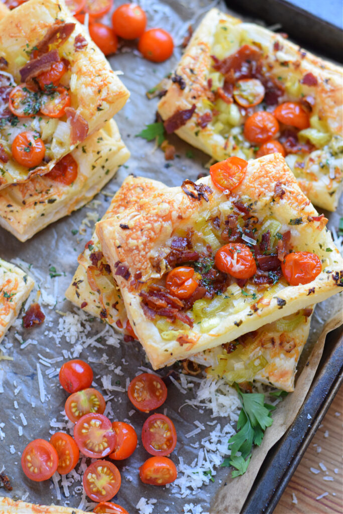 Tomato leek and bacon tarts on a baking tray.