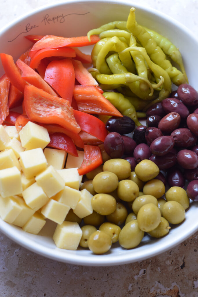 Making an antipasto salad in a bowl.