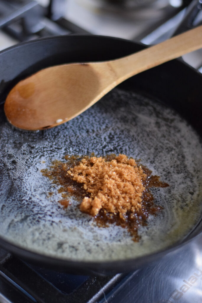 Adding brown sugar to butter in a cast iron skillet.