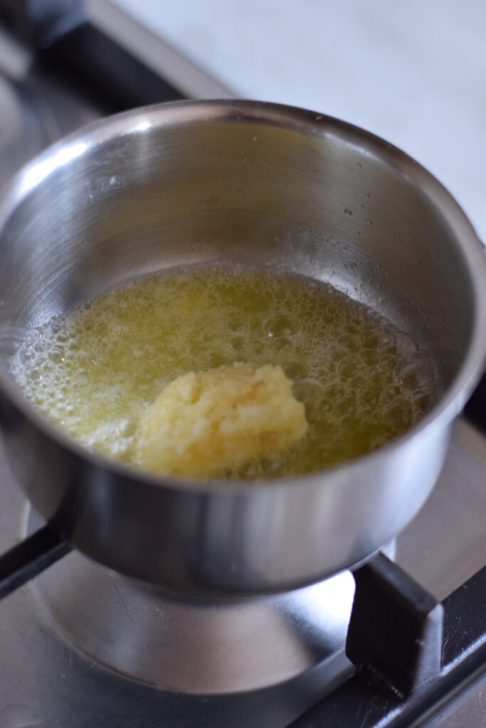 Adding garlic to melted butter.