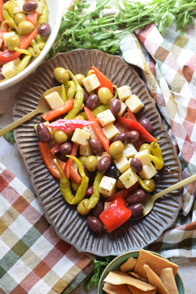 Marinated olives, cheese and peppers on a wooden tray.