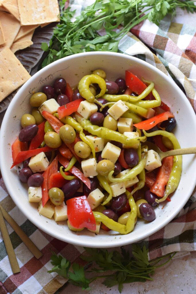 Marinated olives and cheese in a white bowl.