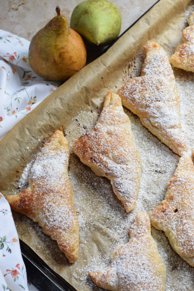 Pear turnovers on a baking tray.