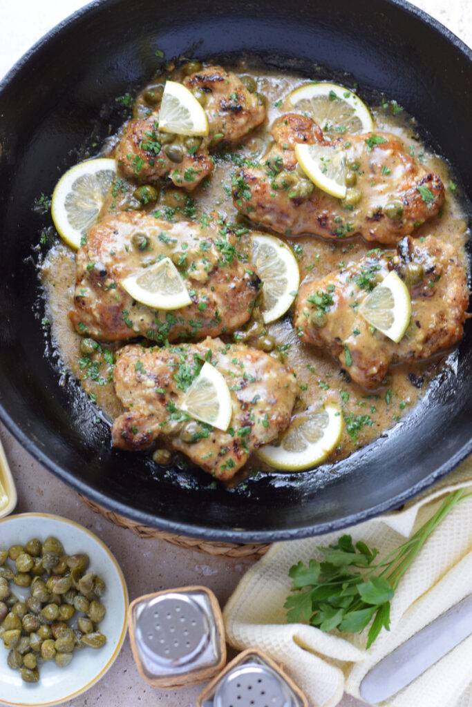 Lemon caper chicken cutlets in a skillet.