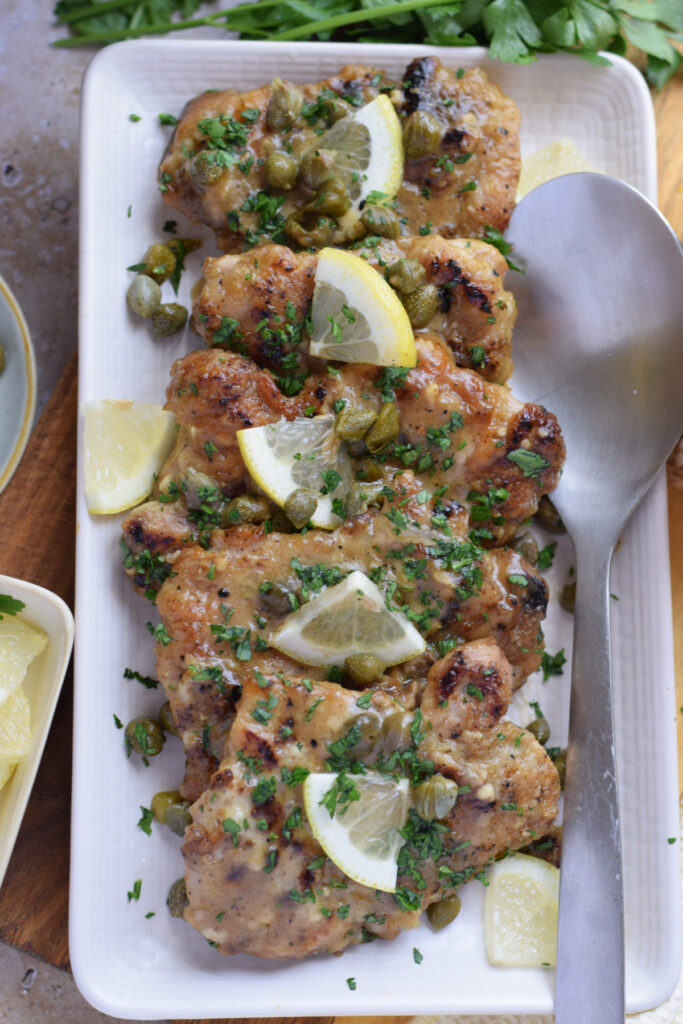 Lemon Caper Chicken Cutlets on a white serving plate.