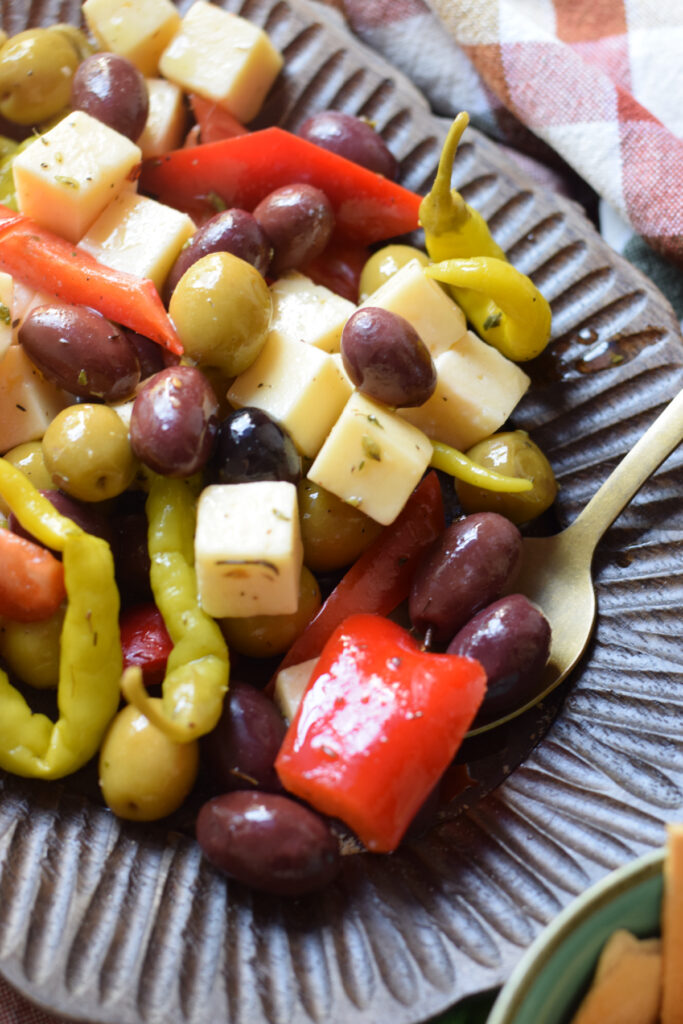 Close up of marinated olives and cheese on a wooden plate.