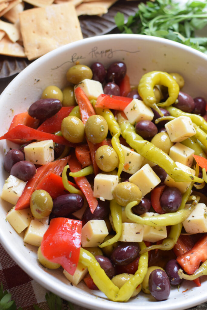 Close up of marinated olives and cheese in a white bowl.