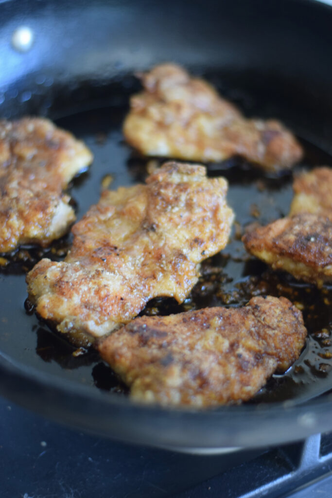 Cooking chicken thighs in a skillet.