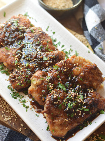 Soy ginger chicken thighs on a white plate.