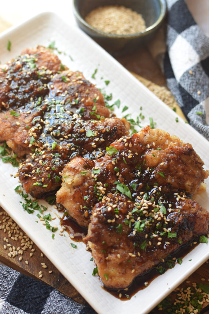 Soy ginger chicken thighs on a white plate.