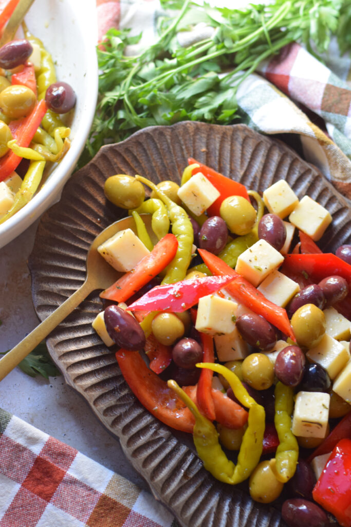 Antipasto olives and cheese in a small wooden tray.