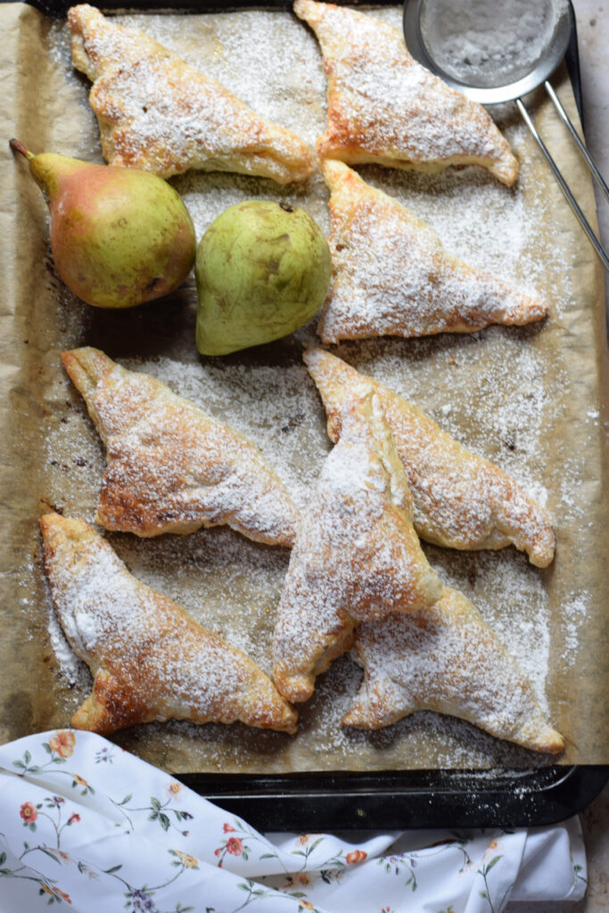 Pear turnovers on a baking tray.