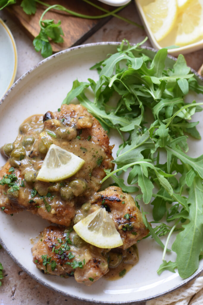 Lemon caper chicken cutlets on a plate.