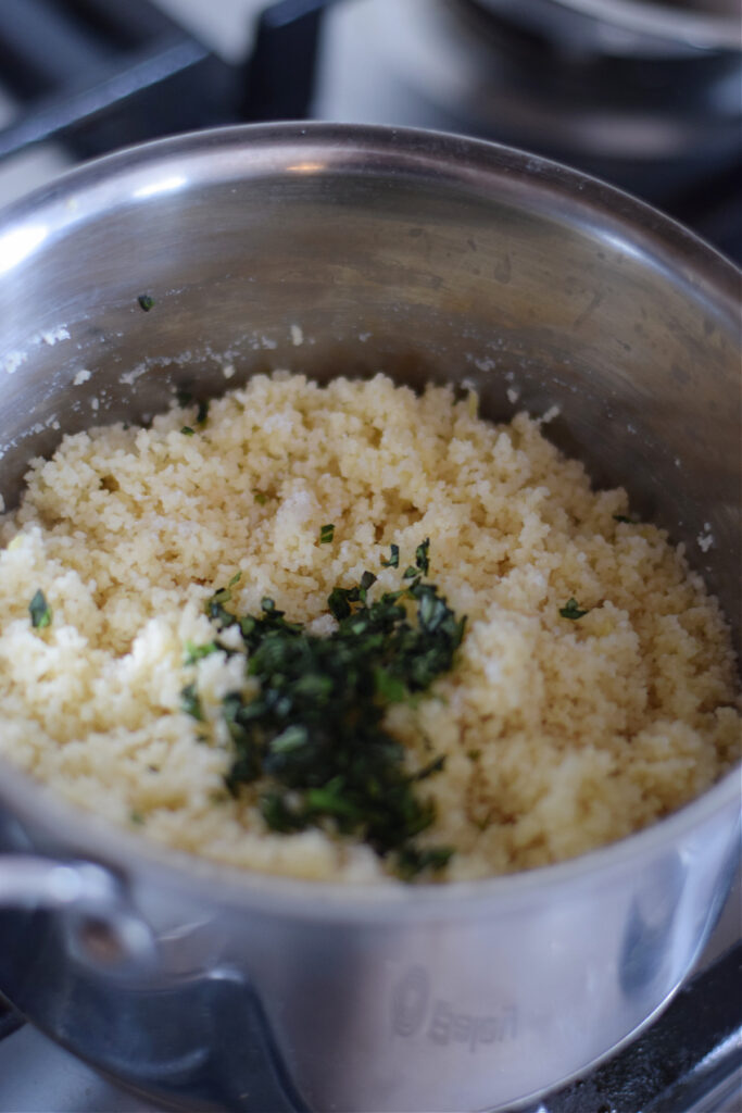 Couscous with fresh basil in a saucepan.