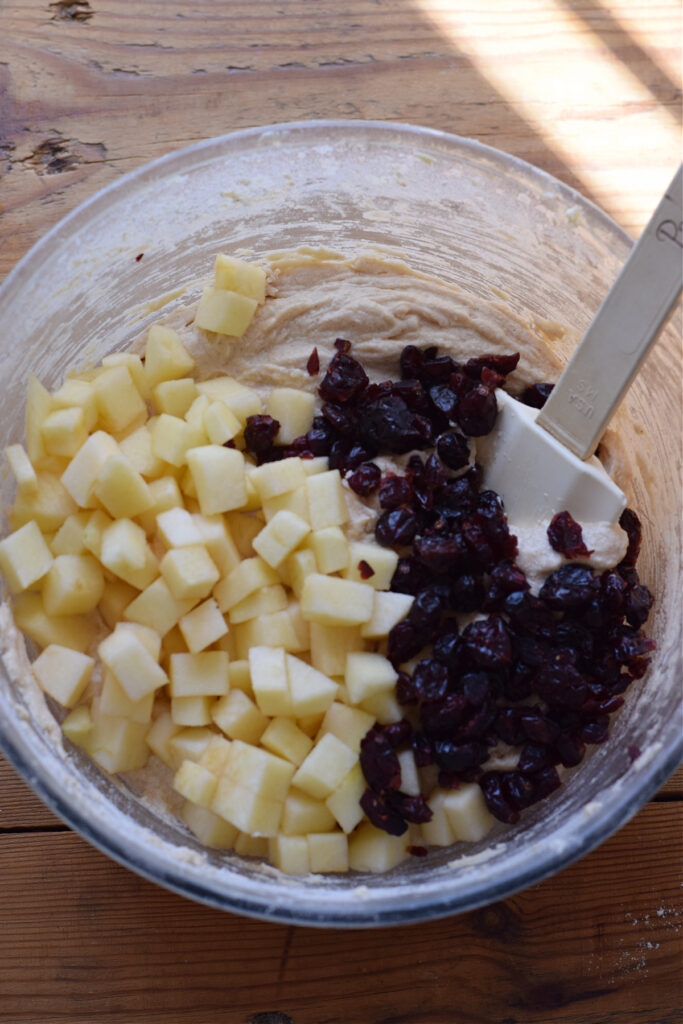 Adding cranberries and apples to muffin batter.