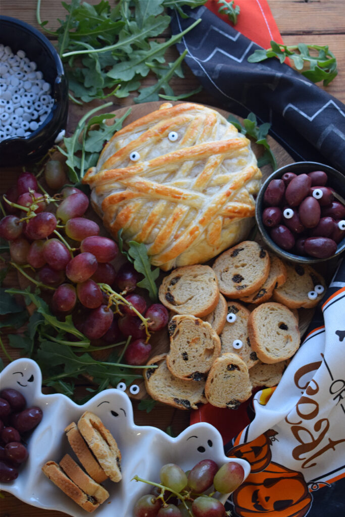 Halloween baked brie on a platter with grapes, olive and crackers.