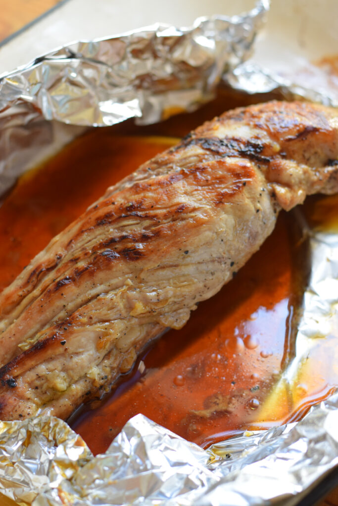 Cooked pork tenderloin on aluminium foil.