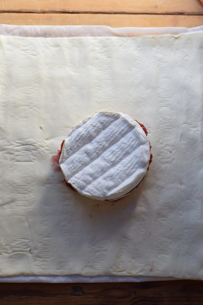 Brie cheese wheel on a sheet of puff pastry.