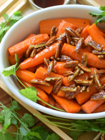 Roasted carrots in a white serving dish.