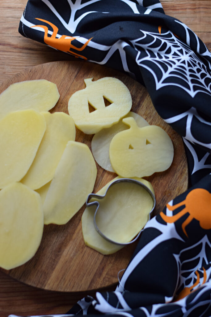 Cutting ou jack-o-lantern potato shapes.