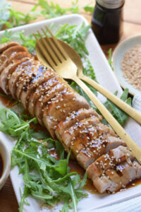 Soy glazed pork tenderloin on a white plate.