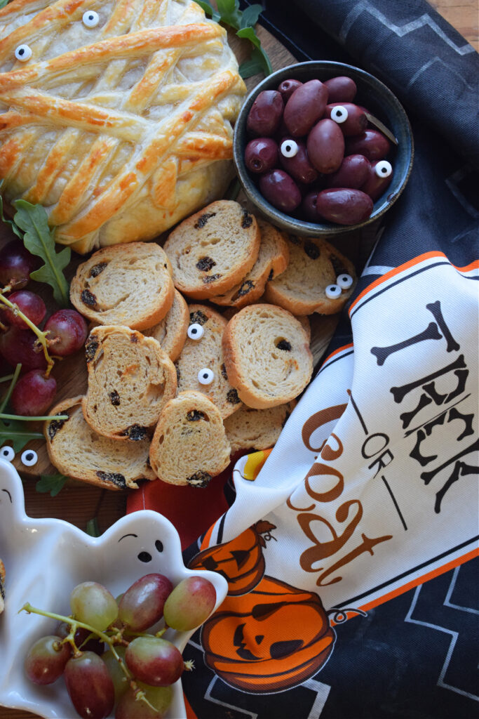 Baked brie on a platter with cheese and crakders.