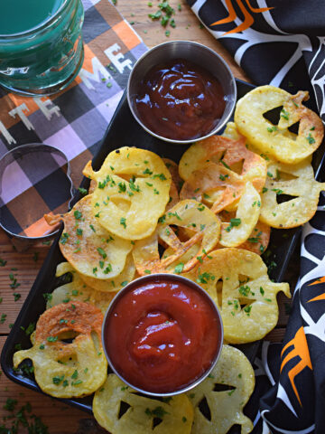 Halloween style potato chips on a plate with ketchup.