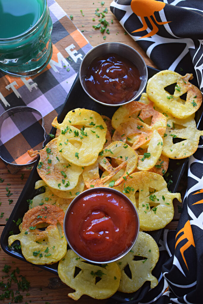 Halloween style potato chips on a plate with ketchup.