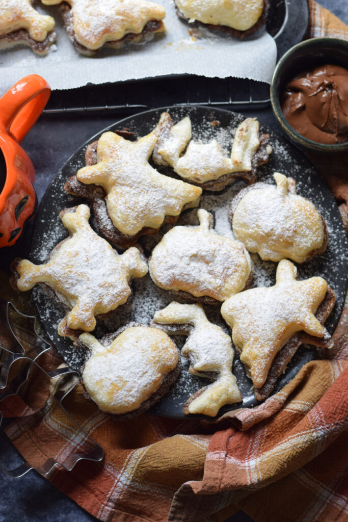 Nutella puff pastry shapes on a black plate.