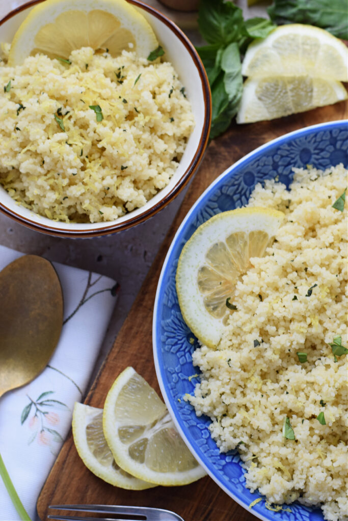 Lemon basil couscous in a blue bowl with lemon slices.