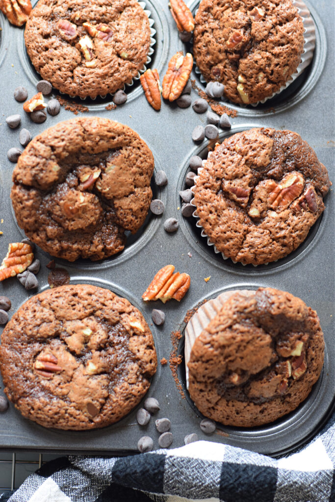 Chocolate pecan muffins in a muffin tin.