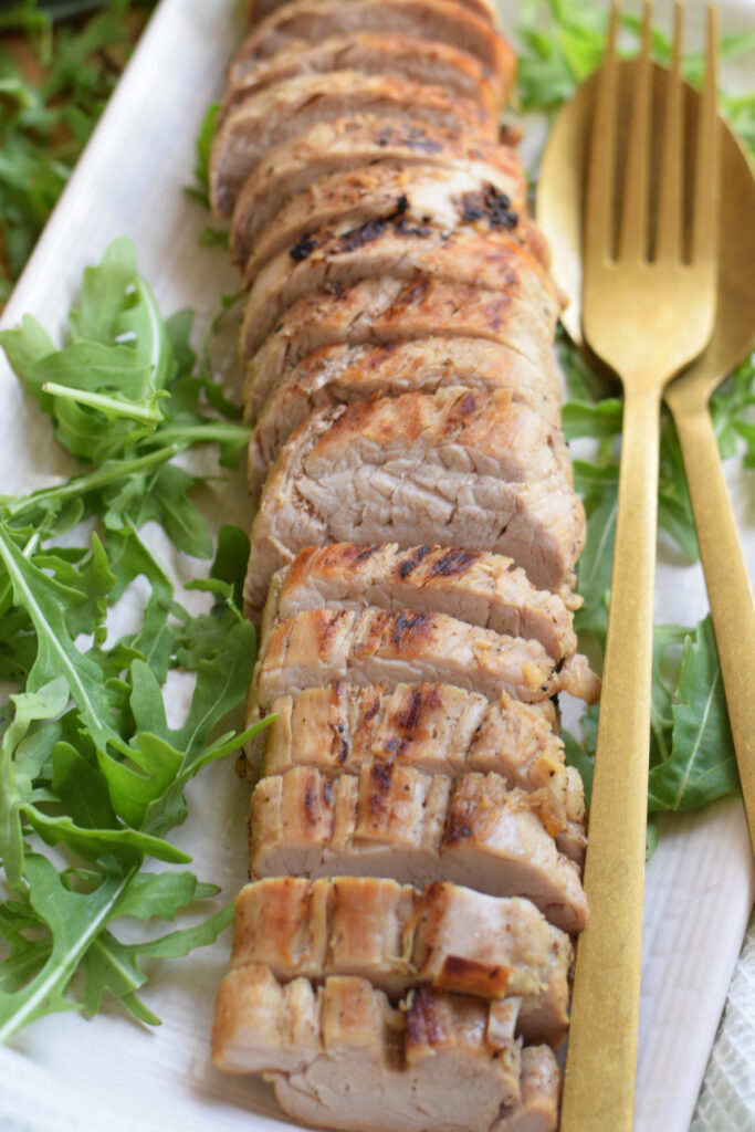 Sliced pork tenderloin on a white plate.