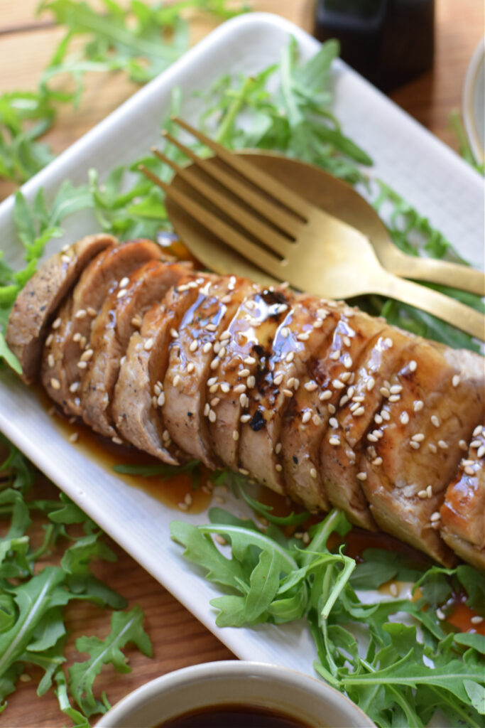 Close up of pork tenderloin on a white plate.