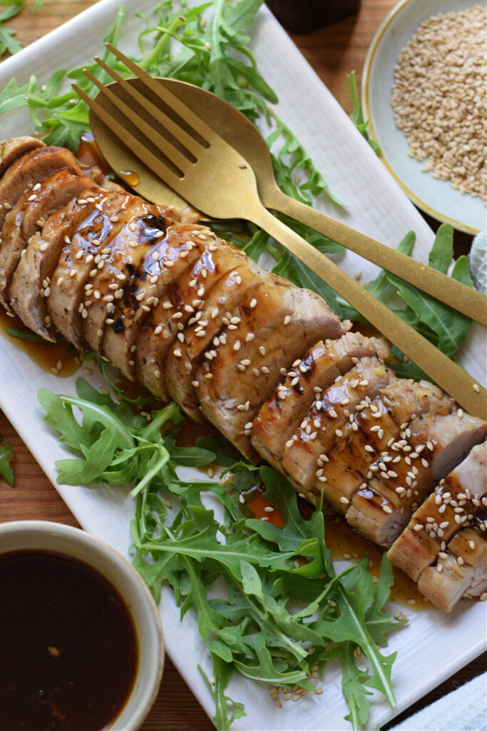 Pork tenderloin on a tray with a fork and spoon.