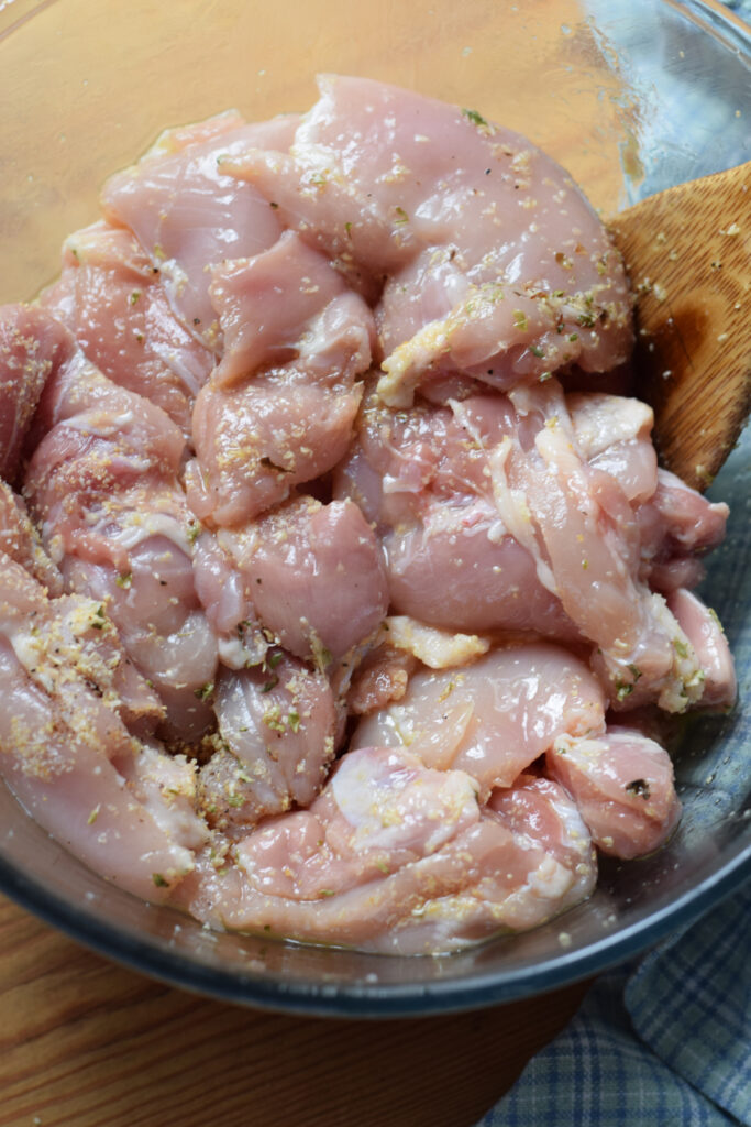 Marinading chicken in a glass bowl.