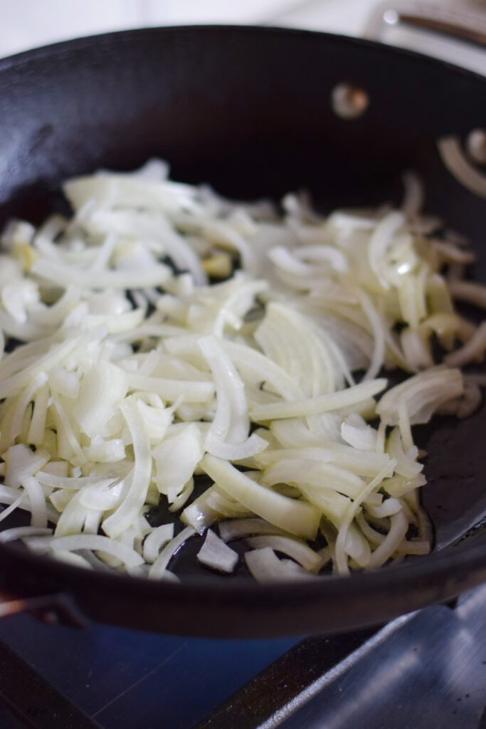 Adding onions to a skillet.