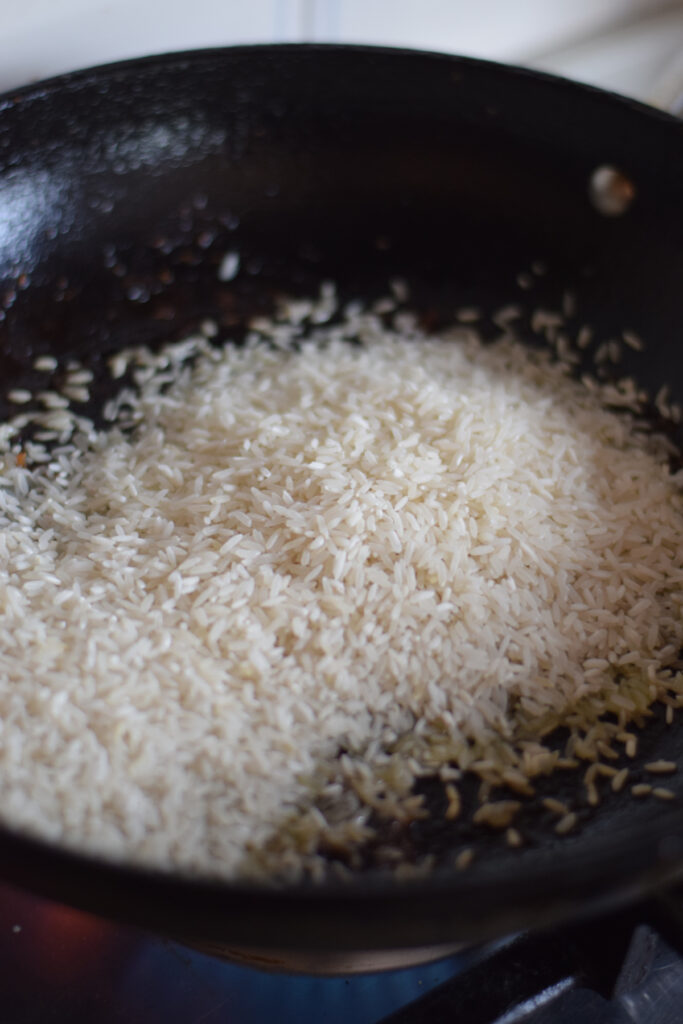 Adding rice to a cast iron skillet.